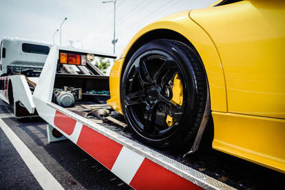 Yellow sports car resting on a white flatbed tow truck.